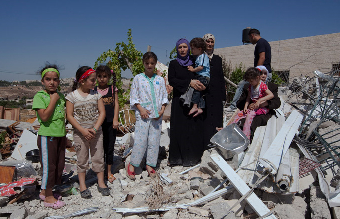 A Palestinian family stands in the remains of their house, that has been demolished by the Israeli authorities in the Beit Hanina neighborhood